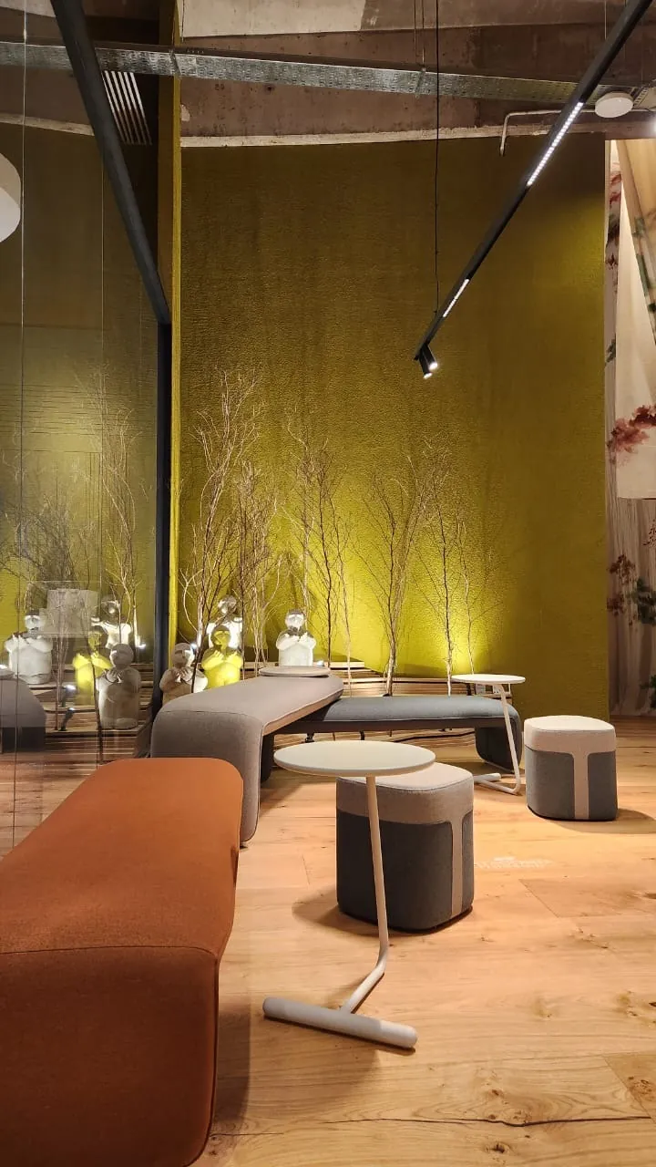 Maximalismo urbano: el color vuelve a ser protagonista (lo que vimos en Casa FOA 2025) Sala de estar con pared verde oliva, estructura a la vista, piso de madera y banco color terracota